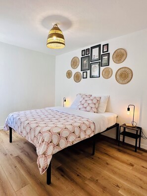 Ein Schlafzimmer mit Bett, Nachttischen, einer Hängeleuchte und Wanddekorationen.