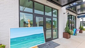 A gallery entrance with a large painting of a beach scene, a doormat with the gallery's name, and potted plants outside. - Stay at The Hut! Room for Everyone! 4BR Fun Sleeps 11 (Santa Rosa Beach)