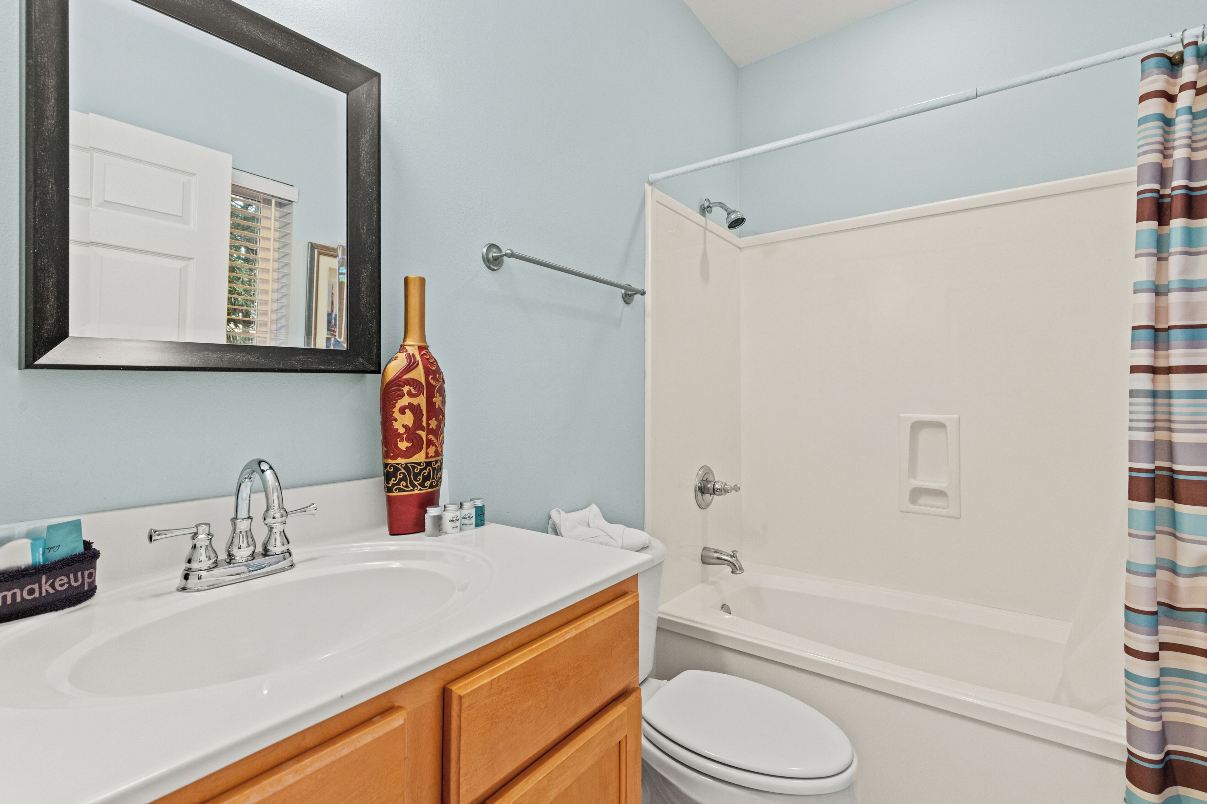 A bathroom with a sink, mirror, toilet, and shower.