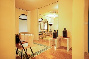 Un hall de hotel con una zona de estar, una mesa con una computadora portátil y faroles decorativos.