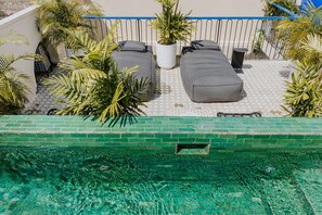 Eine Dachterrasse mit Pool, Liegestühlen und Topfpflanzen.
