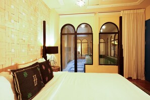 Ein Hotelzimmer mit Bett, Lampe, Spiegel und Blick auf einen Pool durch eine Glastür.