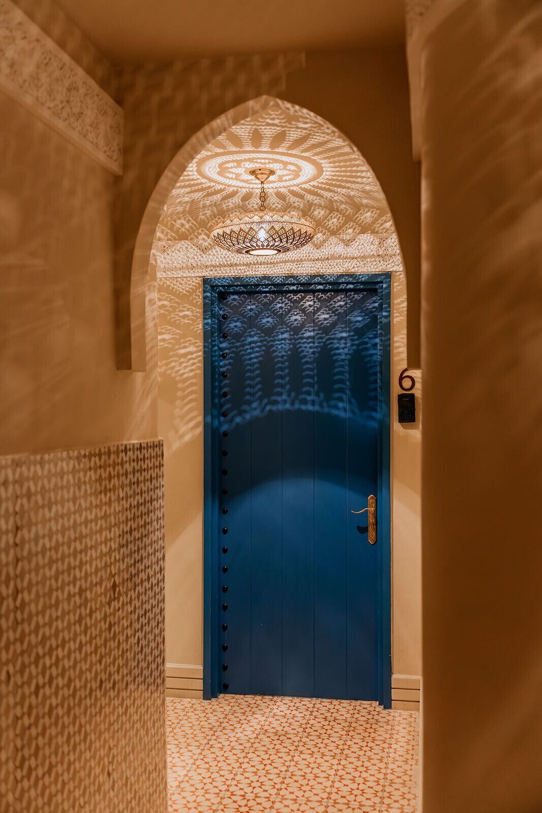 A blue door with a patterned wall and a textured floor.