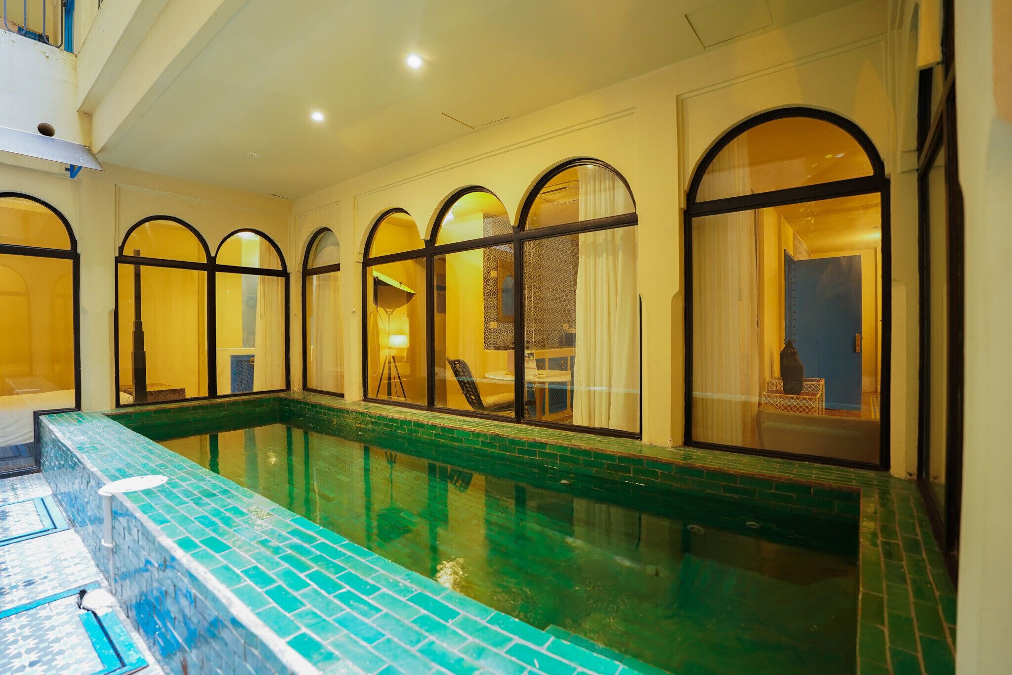 A swimming pool with arched windows and a tiled deck.