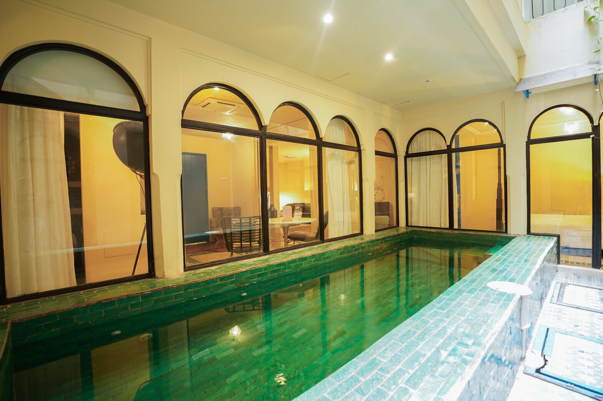 An indoor swimming pool with arched windows and a tiled edge.