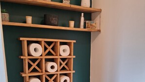 Een badkamer met een toilet, houten planken en toiletpapierrollen.