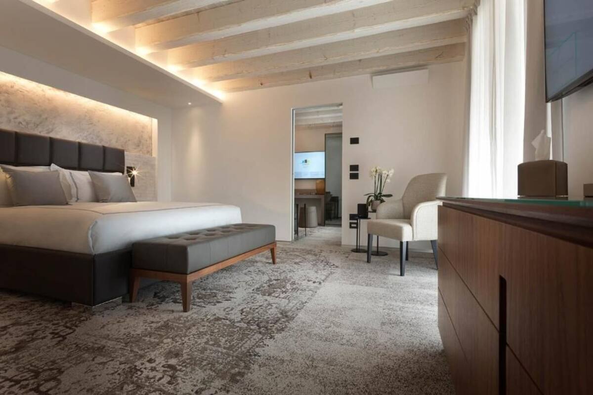 Ein modernes Schlafzimmer mit einem großen Bett, einer kleinen Sitzecke und einem Fernseher.