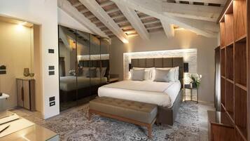 A bedroom with a large bed, a bench, a wardrobe, and a mirror.