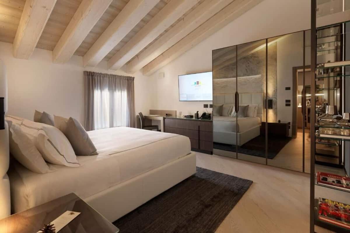 Ein modernes Schlafzimmer mit einem großen Bett, einem Schreibtisch, einem Kleiderschrank und einem Fernseher.