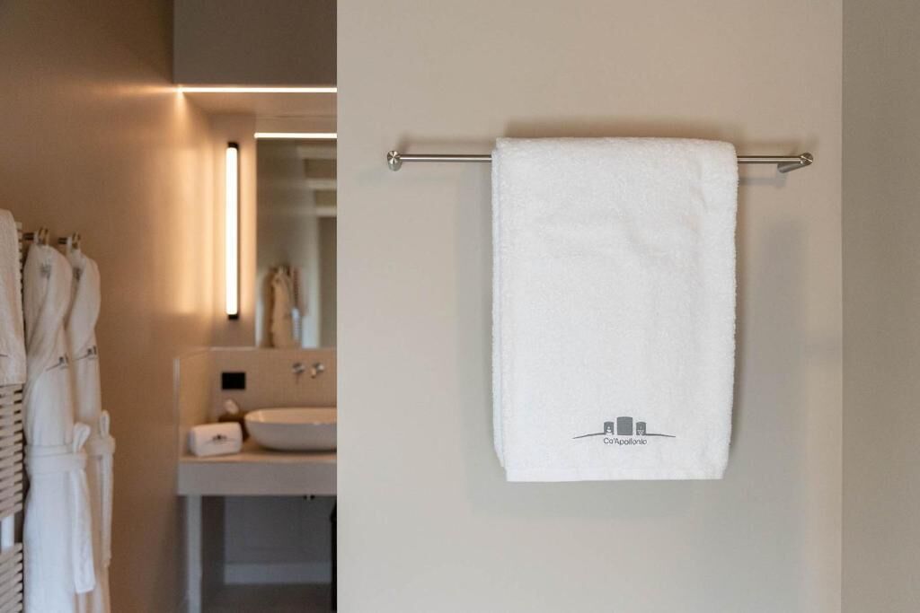 Une salle de bain avec une serviette suspendue à un porte-serviettes en métal, un lavabo et un miroir.