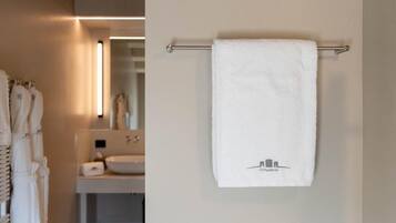 Une salle de bain avec une serviette suspendue à un porte-serviettes en métal, un lavabo et un miroir.