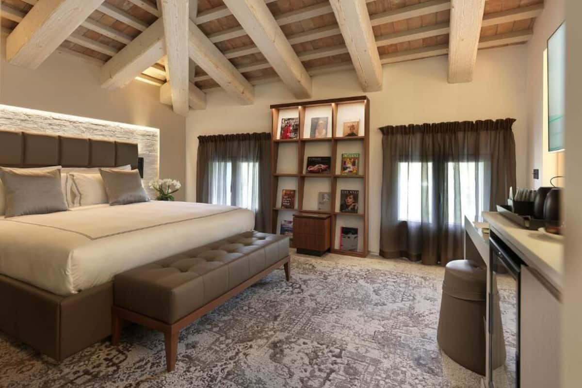 Ein Schlafzimmer mit einem großen Bett, einer Bank, einem Bücherregal und einem Schreibtisch.