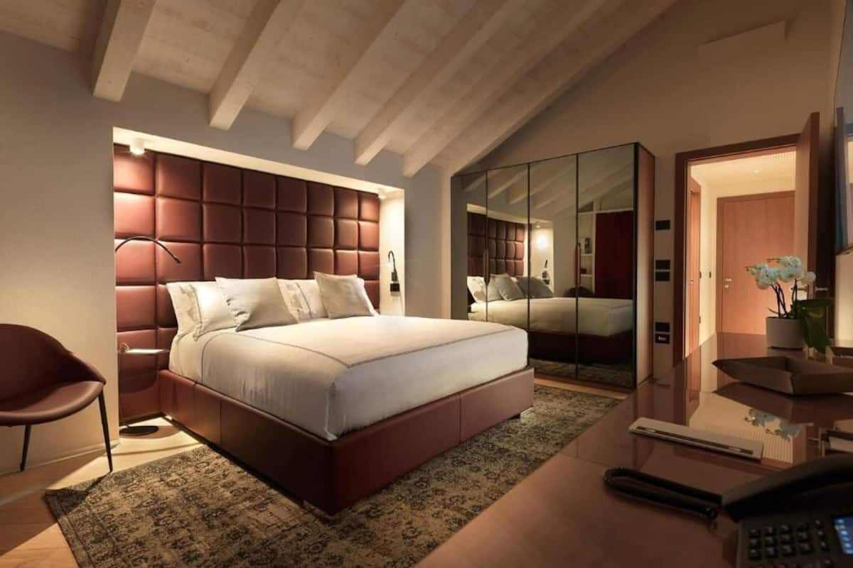 Ein modernes Schlafzimmer mit einem großen Bett, einem Schreibtisch und einem Schrank mit Spiegel.