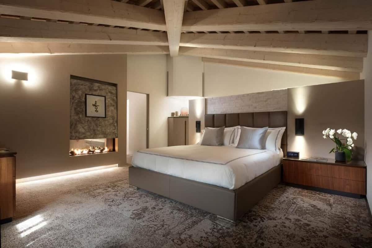 Ein Schlafzimmer mit einem großen Bett, einem Nachttisch, einer Wandleuchte und einem kleinen Tisch mit einem Blumenstrauß.