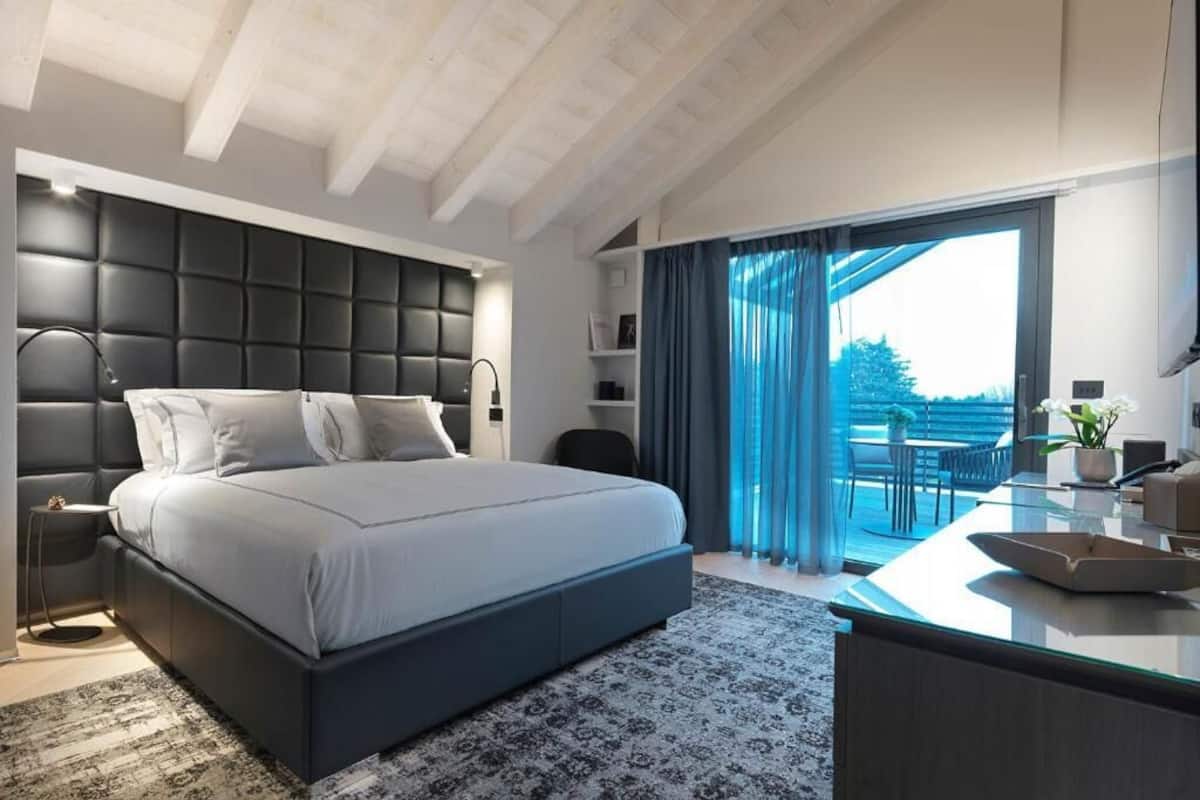 Ein modernes Schlafzimmer mit einem großen Bett, einem Schreibtisch und einem Balkon mit Vorhängen.