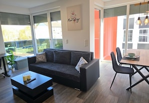 A modern living room with a sofa, coffee table, and dining area. - Free Parking & Balcony upper floor flat - APOLONIAliving (Karlsruhe)