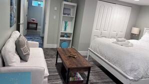Ein Schlafzimmer mit einem Bett, einem hölzernen Couchtisch, einem weißen Kleiderschrank und einem weißen Sofa.