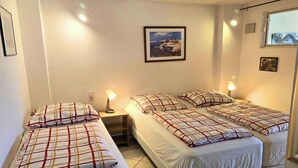 A room with two beds, a nightstand, a lamp, and a framed picture on the wall. - Mobile Home im Ferienpark mit Seezugang (Dabel)
