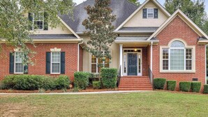 A two-story house with a brick facade, a front porch, and a well-maintained lawn. - 11 miles to the Augusta National Golf Club! Your home for the Masters Tournament (Grovetown)