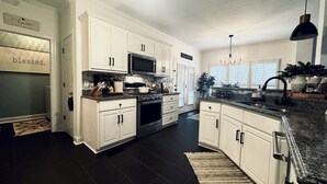 A modern kitchen with white cabinetry, a microwave, stove, and a large island with a sink. - 11 miles to the Augusta National Golf Club! Your home for the Masters Tournament (Grovetown)
