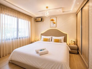 A hotel room with a large bed, a bedside table, an air conditioning unit, a wall-mounted light fixture, and a window with curtains. - Chic apartment with parking and wifi, close to all amenities (Fes)