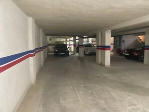 A parking garage with multiple levels and columns, featuring a red, white, and blue striped pattern on the walls. - Chic apartment with parking and wifi, close to all amenities (Fes)