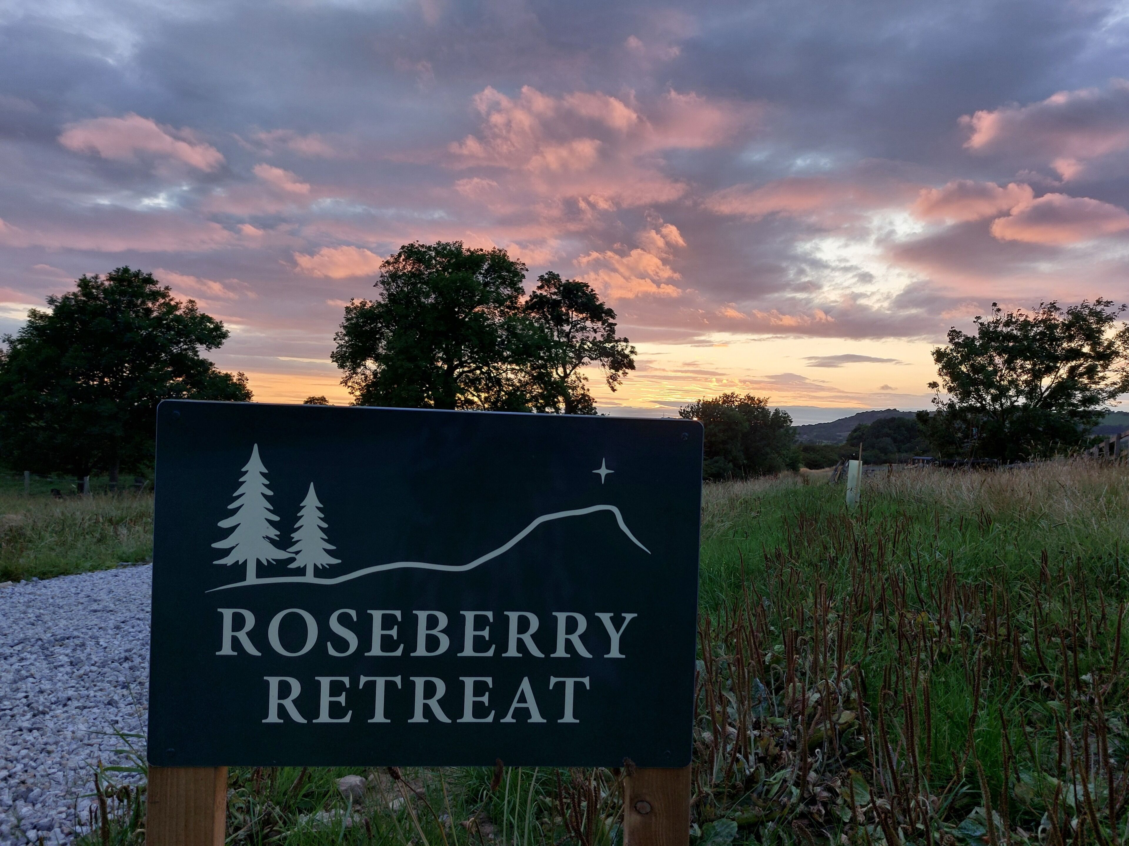 Schild für Roseberry Retreat mit Berg- und Baumgrafik.