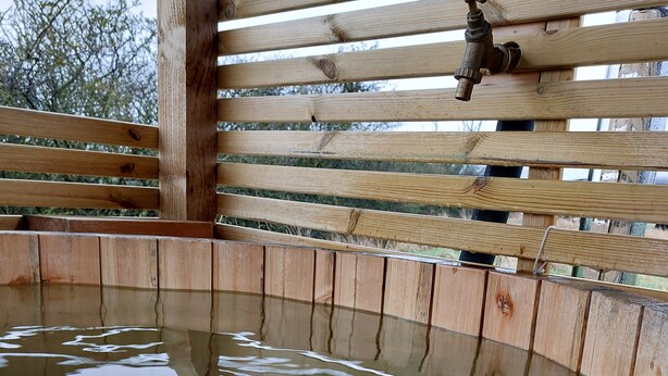 A wooden deck with a wooden fence and a water feature. - The Old Library Shepherd's Hut with Hot Tub, on the edge of the North York Moors (Pinchinthorpe)