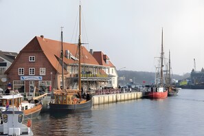 A waterfront building with a red roof, a signboard, and a dock with boats.