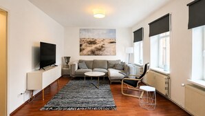 Un salon moderne avec un téléviseur à écran plat, un ensemble de canapés, une table basse et un tapis à motifs.