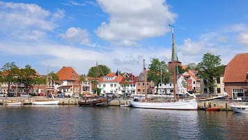 Een haven met aangemeerde boten, gebouwen met rode daken en een heldere blauwe lucht.