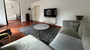 Un salon moderne avec un canapé, un téléviseur, une table basse et un tapis à motifs.