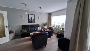 Un salon comprenant un canapé, deux fauteuils, une table basse et une plante en pot.