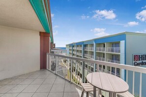 A hotel balcony with a view of the ocean, a tiled floor, and a table and chair. - Harbour Place 502 (Orange Beach)