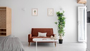 En moderne stue med en brun sofa, et hvidt sofabord og en høj, grøn plante.
