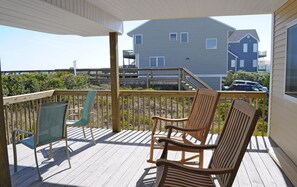 A wooden deck with two chairs and a table, overlooking a residential area with a house and a pier. - Southern Aire - a spacious 5-bedroom oceanfront in Surf City, NC (Surf City)
