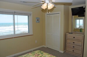 Une chambre avec vue sur l’océan, un ventilateur de plafond, une commode et un placard.