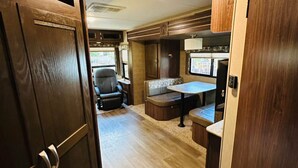 Interior compacto de autocaravana con kitchenette, zona de comedor y espacio de estar.