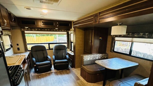 Interior compacto de autocaravana con kitchenette, dos sillas, una mesa de comedor y una pequeña zona de estar.