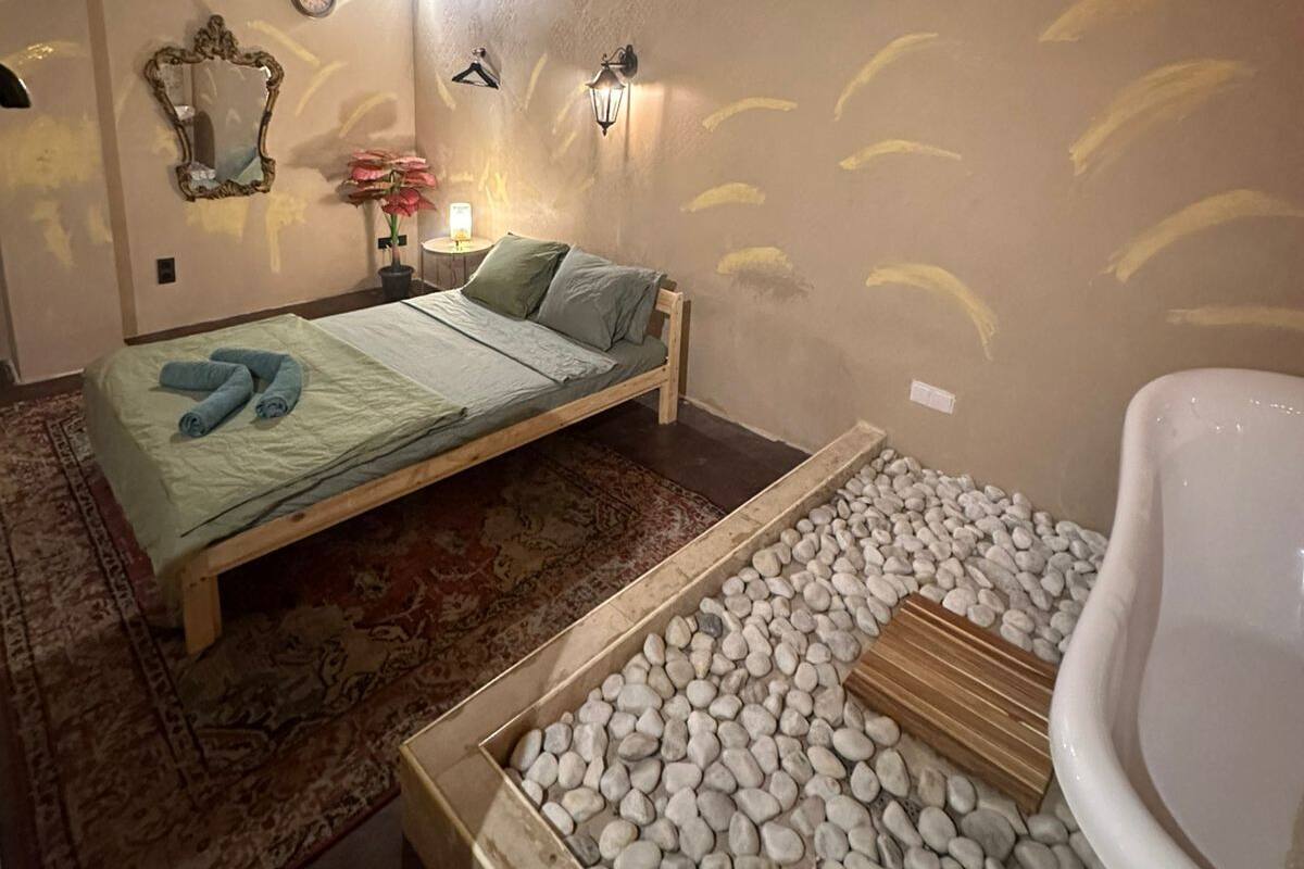 A bedroom with a bed, a nightstand, a mirror, and a wall clock.