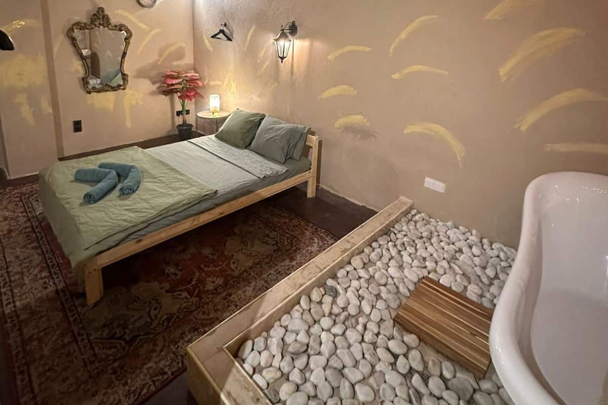 Un dormitorio con cama, mesita de noche, espejo y un reloj de pared.
