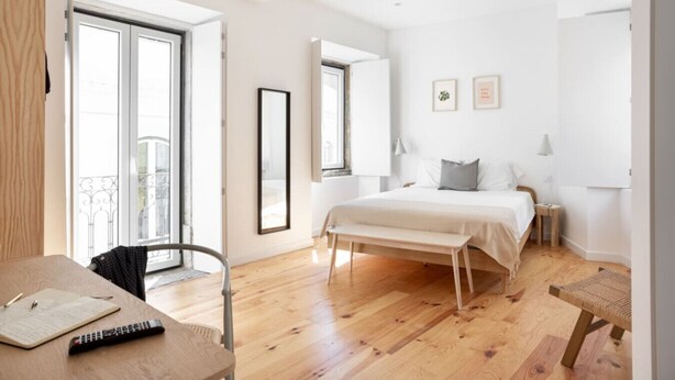A modern bedroom with a large bed, bedside tables, a desk with a chair, and a balcony view. - Spacious 6-Bedroom Apt w/ Sunny Terrace in Lisbon (Lisbon)