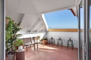 A rooftop terrace with a table, chairs, potted plants, and bar stools. - Spacious 6-Bedroom Apt w/ Sunny Terrace in Lisbon (Lisbon)