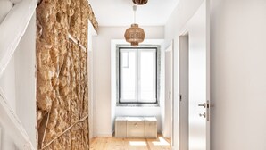 A hallway with a stone wall, a wooden floor, a window with a view, and a door. - Spacious 6-Bedroom Apt w/ Sunny Terrace in Lisbon (Lisbon)