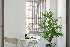 A small balcony with a white chair, a table with a bowl of fruit, and a potted plant. - Spacious 6-Bedroom Apt w/ Sunny Terrace in Lisbon (Lisbon)