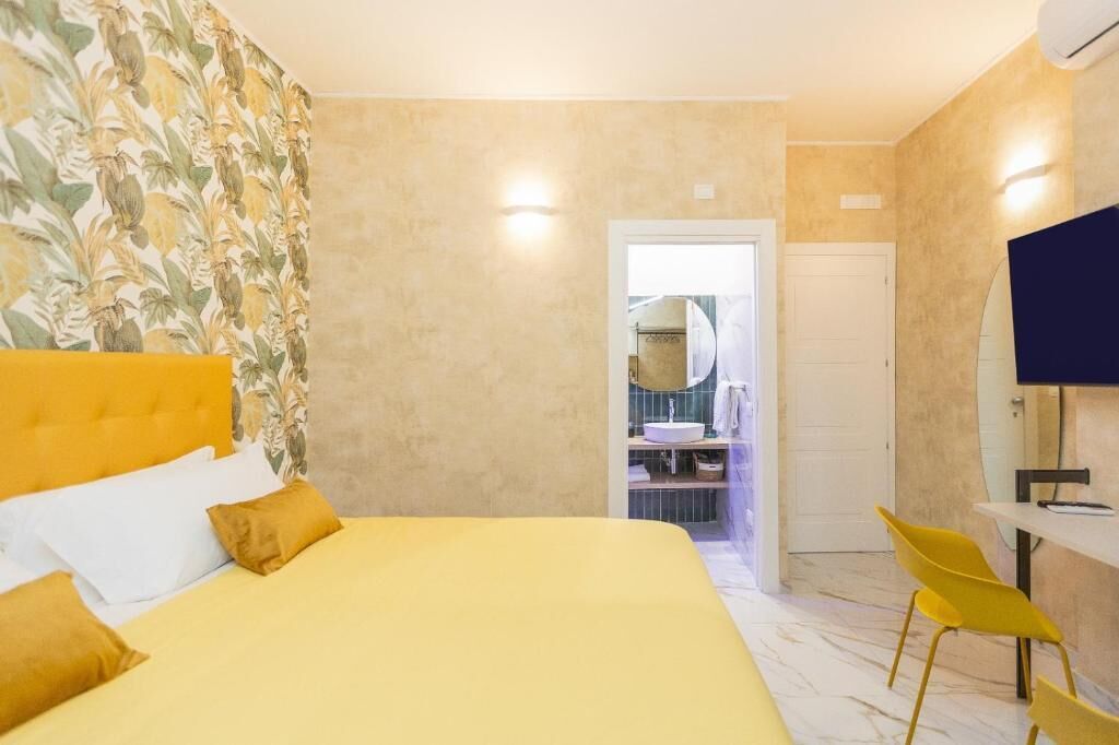 A hotel room with a bed, a bathroom with a sink, and a TV.
