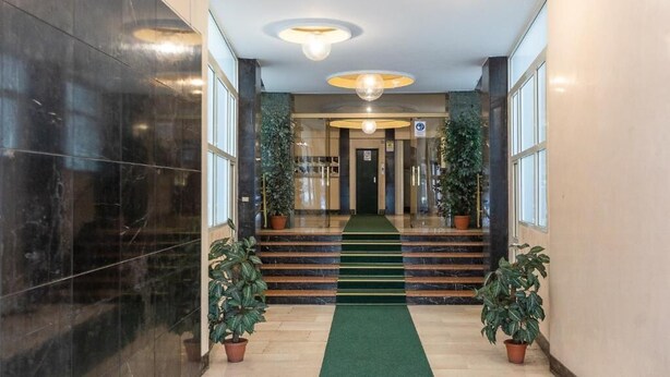A hotel lobby with a marble floor, a green carpeted staircase, and potted plants. - Flowery Rainbow (Rome)