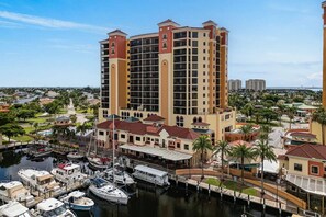 Ein Hochhaus-Hotel mit zahlreichen Balkonen, eine Marina mit Booten und eine Marina mit überdachtem Gang.