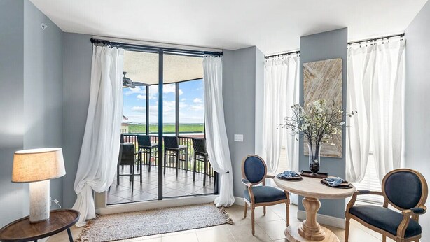 A room with a view, a table with chairs, a lamp, and a window with curtains. - Cape Harbour Luxury Condo, 2 King Beds, Pool, Shops & Restaurants (Cape Coral)