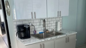Eine moderne Küche mit weißen Schränken, einer Spüle, einer Kaffeemaschine und einer Marmorarbeitsplatte.